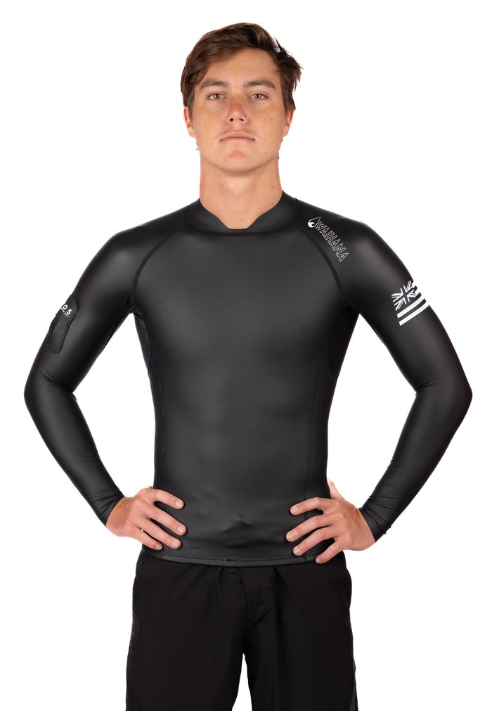 Male model wearing a black Waihana WAI-FLEX long-sleeve surf top impact suit with Hawaiian flag graphic on the sleeve, posed with hands on hips against a white background.