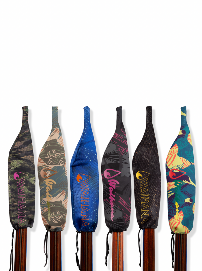 Six Waihana Neoprene Protective SpearSocks lined up on wooden pole spear shafts, showcasing all pattern variants including Goliath Grouper, Tropicam Green, Bimini Brushstroke, Kajiki Blue, Hawaiian Brushstroke, and Pink Fishbone.
