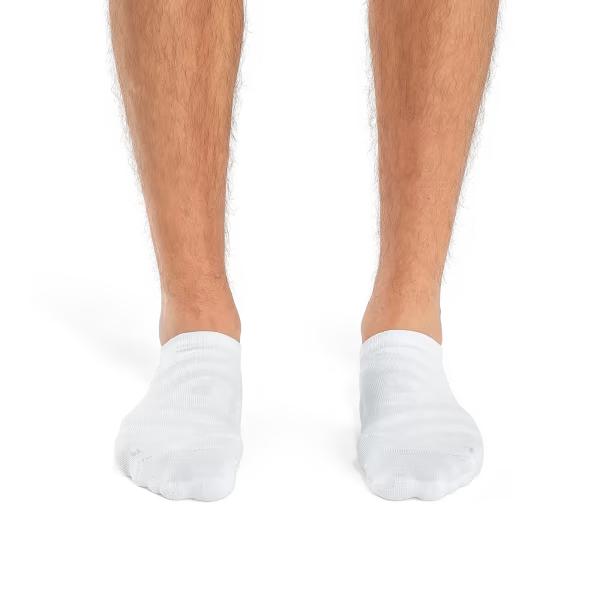 White On Running low-cut performance socks featuring breathable mesh panels and arch support on a runner's feet.