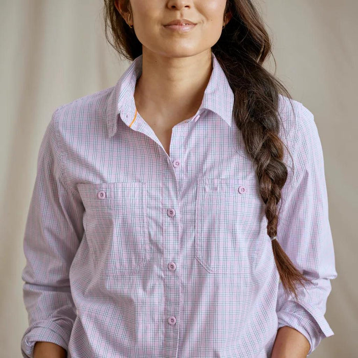 Woman wearing a light pink and blue plaid Orvis River Guide long-sleeve shirt with button-front pockets.