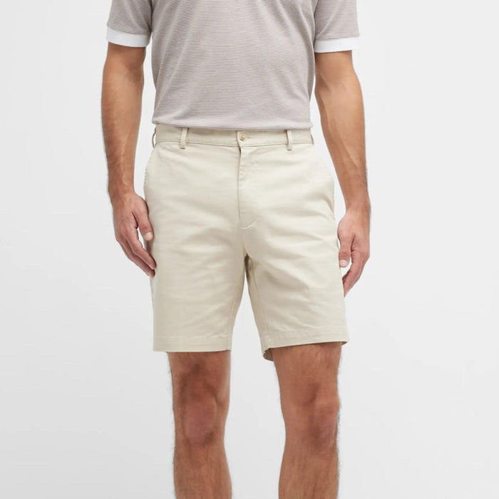 Man wearing beige Peter Millar Pilot Twill shorts in a classic fit with a button closure and belt loops.