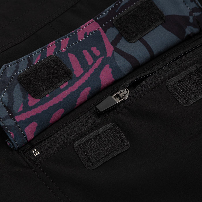 Close-up of Waihana Pink Fishbone W1 Board Shorts featuring a dark blue and magenta camo-print waistband with velcro closures and a black zipper pocket on black fabric.