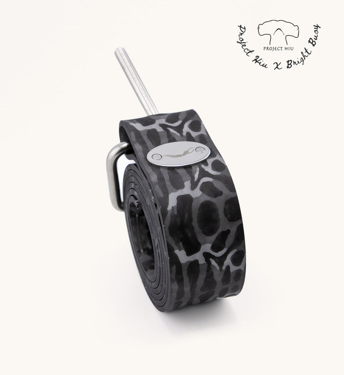 Rolled grey and black tiger shark print silicone weight belt with stainless steel buckle and pin, featuring the Project Hiu X Bright Buoy collaboration logo.