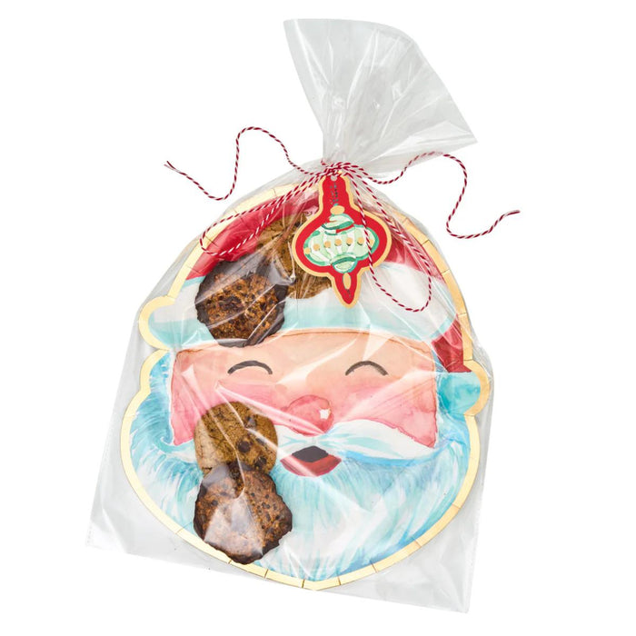 Santa-shaped paper cookie tray in a clear gift bag with red and white twine and a decorative ornament gift tag.