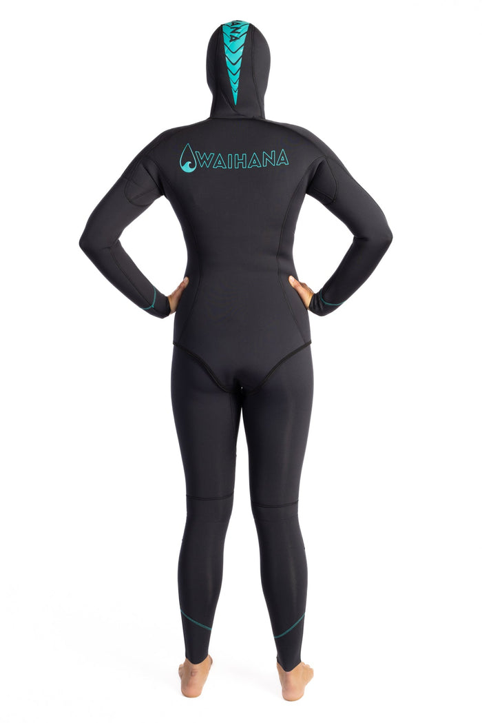 Back view of a woman wearing the Waihana Women's Essentials black hooded wetsuit with teal logo and chevron hood accent on a white studio background.